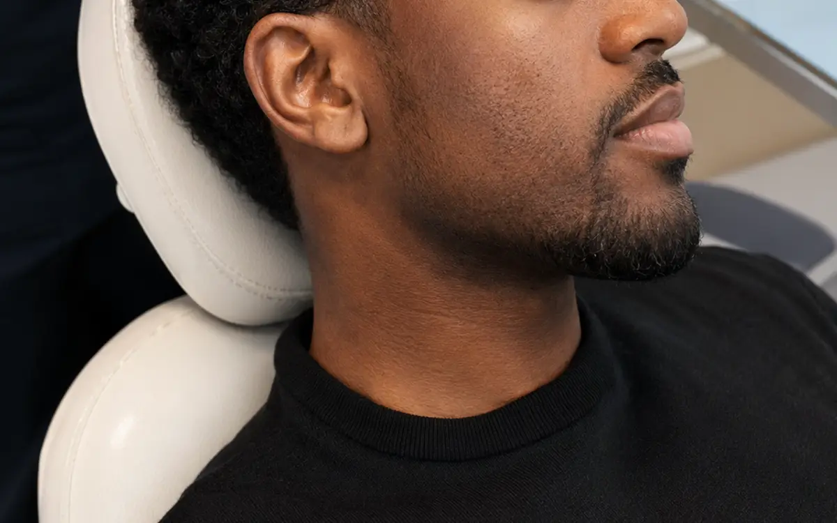A man receiving a platelet-rich plasma scalp injection, with a tube of separated plasma beside him
